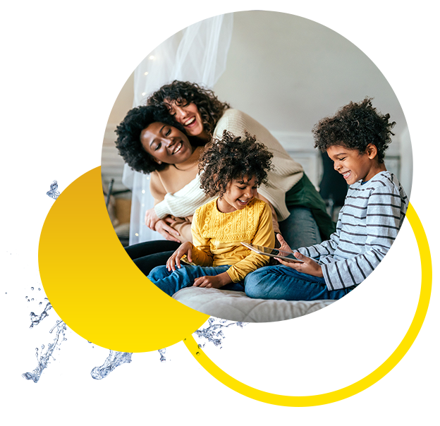 A happy family of three sits together on a couch, smiling and laughing as they look at a tablet. Playful yellow shapes and water splashes set a cheerful mood, reflecting relief after using chest congestion medication.