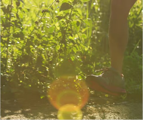 A person jogging outdoors on a sunlit trail, with one leg visible and lush green plants in the background. The image, evoking vitality, subtly suggests how regular activity can complement chest congestion relief or phlegm medication use.